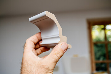 Male hand inspecting against renovation room new wooden composite gray painted moulding cornice © ifeelstock