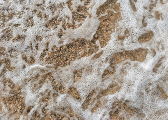 Foamy, bubbling, large sea waves close-up mixed with sand.