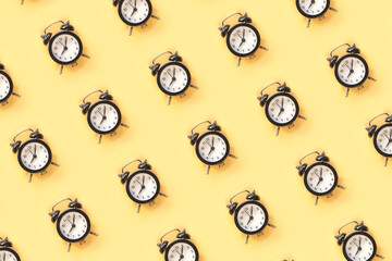 Pattern made of alarm clock on yellow background, top view, flat lay
