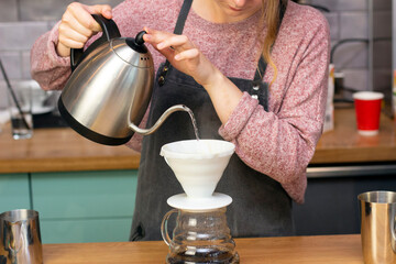 barista makes espresso using a funnel. The process of making coffee in the prover. Spilling coffee through the filter funnel from the kettle.