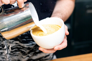 latte art. art of drawing on coffee. barista makes latte art milk from a pitcher