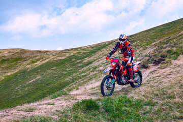 A beautiful landscape of the red mountain with a motorcyclist. Motocross competition.