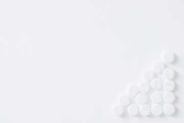 Healthy lifestyle. White paper background and pills arranged in the bottom right corner in the shape of a triangle.