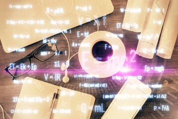 Physics and math theme hologram with formula drawings over computer on the desktop background. Top view. Multi exposure. Concept of education.