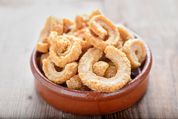 fried pork rinds, in a rustic container on a wooden background