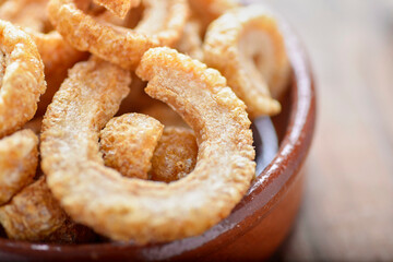fried pork rinds, in a rustic container on a wooden background