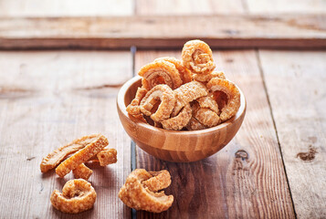 fried pork rinds, in a rustic container on a wooden background