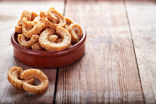 fried pork rinds, in a rustic container on a wooden background