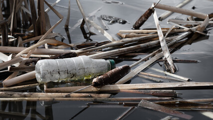 Floating plastic bottle garbage litter in an environmental wetland pond. Pollution impact and...