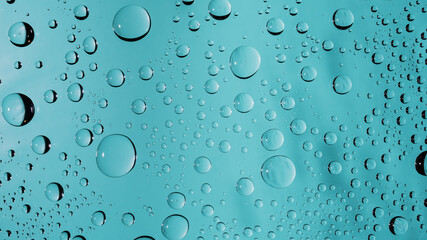 Water drops on turquoise colored glass window surface background. Clear transparent water droplets macro beading wallpaper