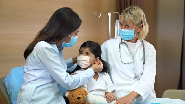 Mother is wearing a cloth mask for little girl protect from virus and Female doctor giving a consultation with mom for safety , illness Air pollution.