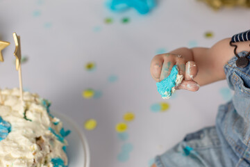 the first cake. blue cake. the child takes the cake with his hand. the hand in the pastry cream. children's holiday