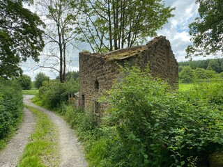 An old stone derelict ruin, surrounded by trees and plants near, Skipton, Yorkshire, UK
