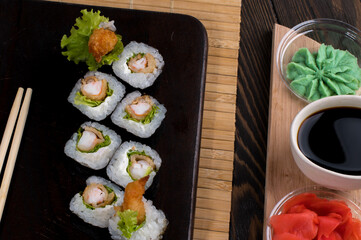 Sushi roll set with salad and fried shrimp on dark background