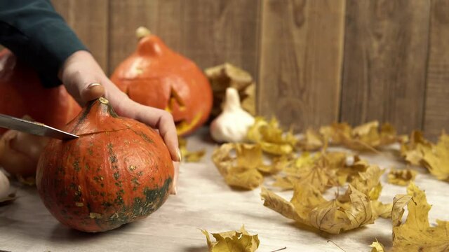 Cutting out the top of a pumpkin for a Halloween lantern decoration. Theme of traditional Hobbies in autumn and cutting out lanterns from vegetables. Mystical traditions in Halloween decorations.