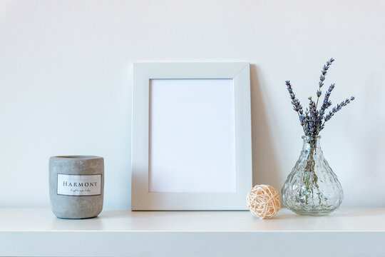 Blank picture frame next to lavender flowers in glass vase and scented candle, mock up.
