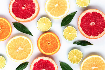 Various sliced citrus fruits: lime, orange, red and yellow grapefruit with green leaves on a white background, texture.