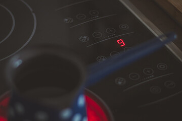 Fototapeta premium Detail of numer 9, maximum heat setting on modern glass or ceramic cooking board while heating a jar of water.