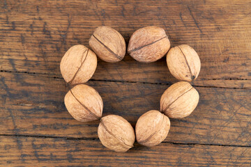 group of fresh raw walnuts on old wooden board background. rustic and detailed image. heart shape.