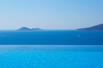 Infinity swimming pool with sea on bright summer day