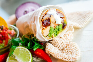 Mexican traditional authentic homemade Burrito with pulled pork beef chili con carne serve with tomato salad and avocado guacamole and dip sauce
