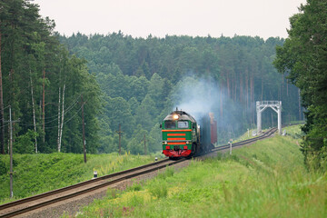 freight train pulls cars and smokes heavily in the forest