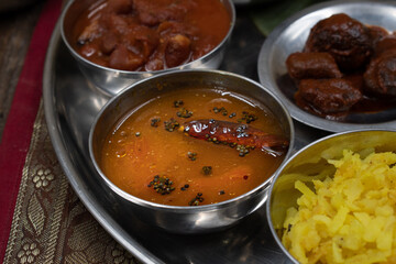 Detail of rasam soup in steel bowl on thali platter