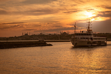 city lines cruise ship sails at the beautiful moment of sunset, summer landscape of istanbul city behind.