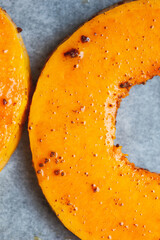 Close up semicircle bright slice of pumpkin prepared for baking in the oven.