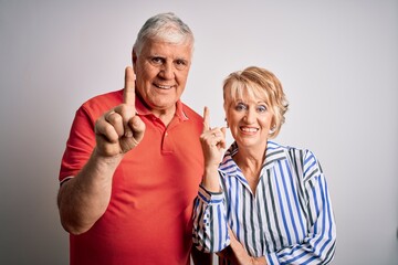 Senior beautiful couple standing together over isolated white background pointing finger up with successful idea. Exited and happy. Number one.