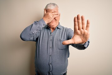 Senior handsome hoary man wearing casual shirt standing over isolated white background covering...