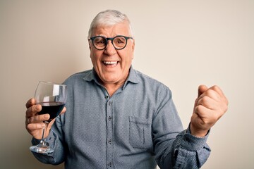 Senior handsome hoary man drinking glass of red wine over isolated white background screaming proud and celebrating victory and success very excited, cheering emotion