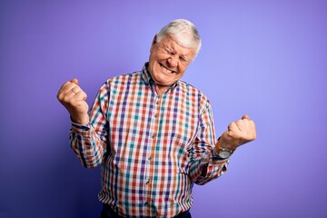 Senior handsome hoary man wearing casual colorful shirt over isolated purple background very happy...