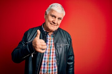 Senior handsome hoary man wearing casual shirt and jacket over isolated red background doing happy thumbs up gesture with hand. Approving expression looking at the camera showing success.