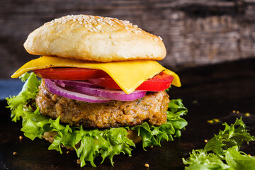 Fresh delicious homemade veggie burger lies on natural slate on rustic wooden background. Delicious tasty burger with lettuce, cheese, onion and tomato. buckwheat and lentil cutlet