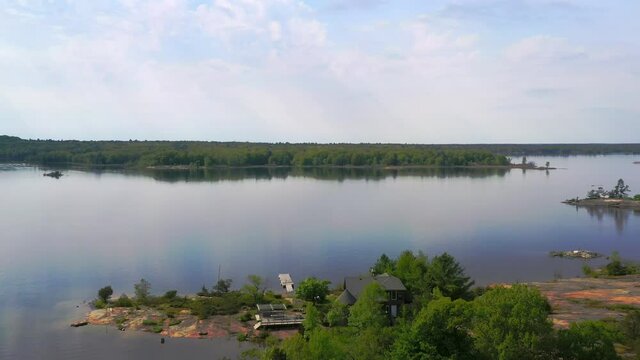 Aerial shot of serene forested island homes on the shores of a great lake