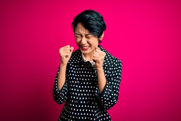 Young beautiful asian girl wearing casual jacket standing over isolated pink background excited for success with arms raised and eyes closed celebrating victory smiling. Winner concept.