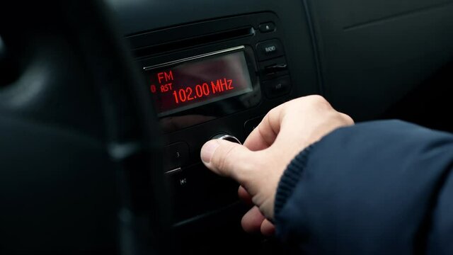 Radio and music in the car. Driver tunes car radio to media radio station frequency 