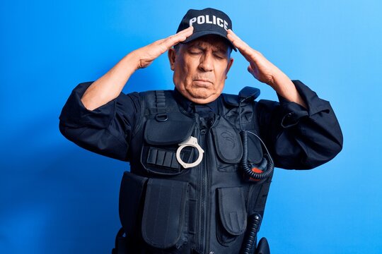 Senior man with grey hair wearing police uniform with hand on head, headache because stress. suffering migraine.