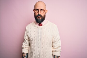 Handsome bald man with beard and tattoo wearing glasses and sweater over pink background depressed and worry for distress, crying angry and afraid. Sad expression.