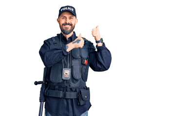 Young handsome man wearing police uniform pointing to the back behind with hand and thumbs up, smiling confident