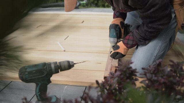 Middle Age Handyman Driving Screws Into Wooden Planks With Cordless Screw Gun.