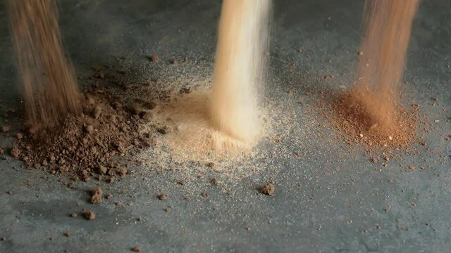 Pouring of different types of soil on dark background