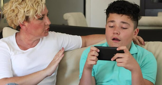 Angry mother taking smart phone from son Nomophobia Disease of the modern age