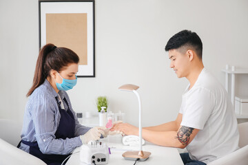 Manicure master working with male client in beauty salon