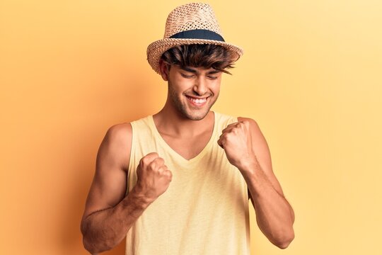 Young hispanic man wearing summer hat celebrating surprised and amazed for success with arms raised and eyes closed