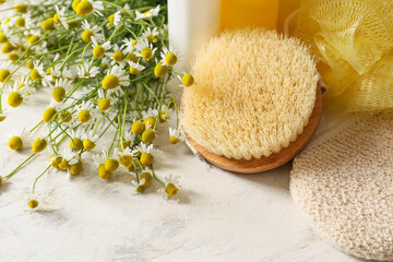 Chamomile flowers and bathing supplies on light background