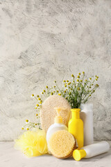 Cosmetics with chamomile flowers and bathing supplies on light background