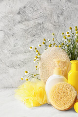 Cosmetics with chamomile flowers and bathing supplies on light background