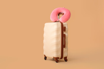 Packed suitcase and travel pillow on color background